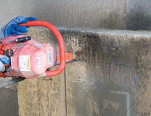 Concrete chain saw scoring the outline of a large rectangle into a concrete foundation