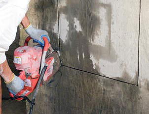 Concrete chain saw cutting the shape of a large rectangle into a concrete foundation