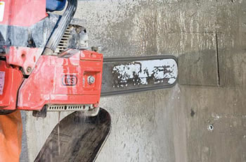 Chain saw scoring a square shape into a concrete wall